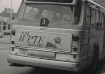 Black-and-white photo of a city bus with a WPTF Radio 680 advertisement displayed on the rear panel.