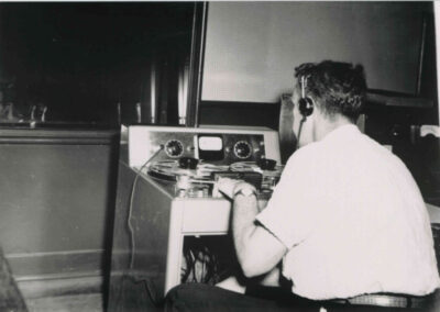 Historic studio photo of a technician wearing headphones while operating a reel-to-reel tape machine at WPTF.