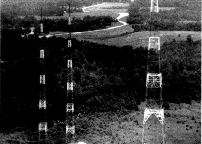 Grainy aerial black-and-white image showing multiple tall WPTF radio transmission towers rising over open fields and rural landscape.